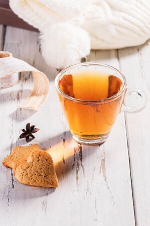 Edible gift. A cup of hot tea with some anise and cinnamon over a wood table. Concept of winter compfort, autumn moodの写真素材