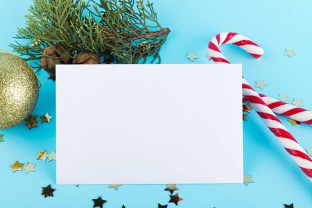 Christmas Candy Canes with golden christmas ball and spruce branch. Christmas decoration on a pastel blue backgound, minimal composition, christmas card, mock up, festive layoutの写真素材