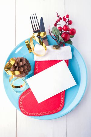 Table setting mock up invitation, place card for celebration Christmas and New Year Holidays on white wooden table. Festive place setting for christmas dinner with red christmas stocking. Top viewの写真素材