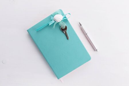mint color notebook with home keys and a pen concept of planing a house buying, mortgage, debt or...
