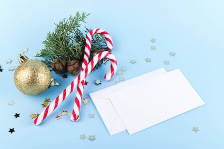 Christmas Candy Canes with golden christmas ball and spruce branch. Christmas decoration on a pastel blue backgound, minimal composition, christmas card, mock up, festive layoutの写真素材