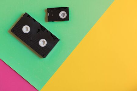 different types of old video cassettes with copyspace on a three-color paper background, minimalism,...