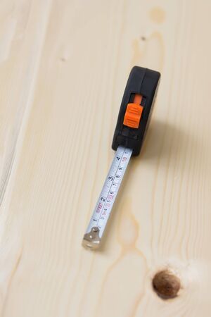 tape measure on the wooden background on a pine board, measurement on building lumber, conceptの写真素材