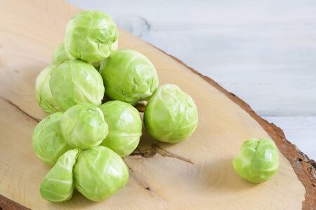 Raw Brussels sprouts, fresh green cabbage on a cutting board on a light background, healthy food and...
