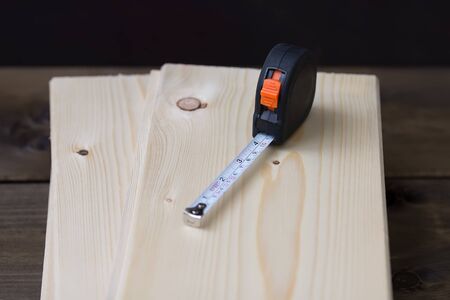 tape measure on the wooden background on a pine board, measurement on building lumber, concept