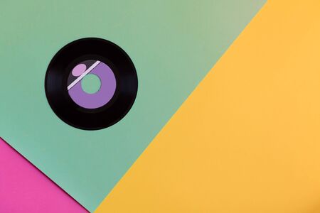One outdated vinyl record on a three-ton paper background: mint, yellow and pink, pop culture. Top view. Minimalism, top view with copy spaceの写真素材