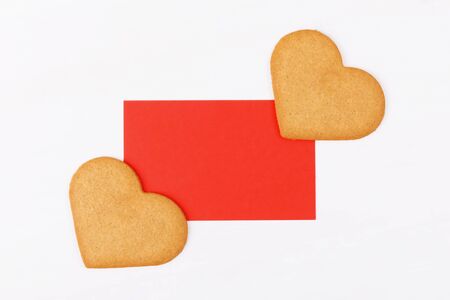Red mockup greenting card with two heart shape cookies on a white backround. Simbol of cozy love and Valentines Day backrgound and festive and birthday concept, copy spaceの写真素材