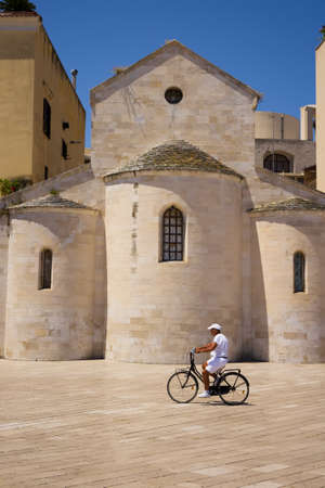 BARI, ITALY - JULY 11, 2018, view of square and man going by bicycle on siesta time in the center of Bari, beside of Vallisa Church building on the Ferrarese squareのeditorial素材