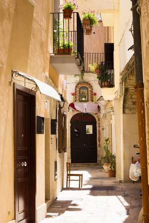 BARI, ITALY - JULY 11, 2018, View of a narrow street in the Italian city Bari, the chair is in the sun, siesta and heat, no one is outdoorsのeditorial素材