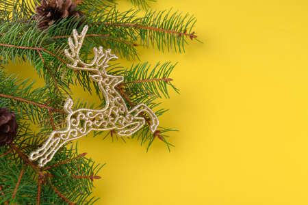 Christmas background of golden golden reindeer decorations with fresh fir tree branch on yellow background, top viewの写真素材