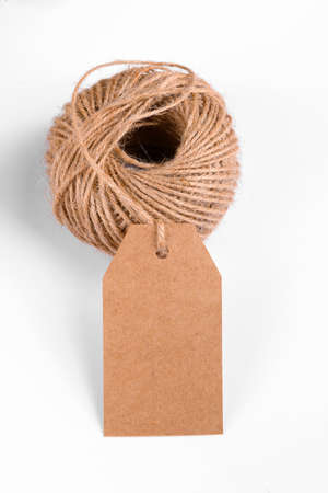 Close-up of craft paper gift tag with skein of rope on white backgroundの写真素材