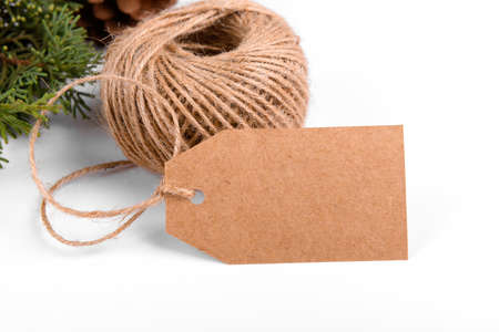 Christmas gift tag mock up of craft paper present label and green fir branch on white background