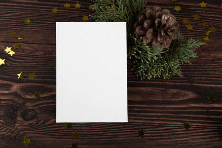 Christmas card mockup template with fir twigs and golden stars on a vintage wooden background....