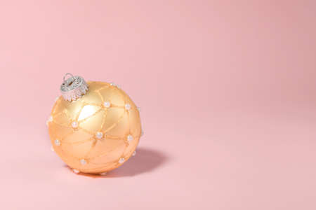 Golden Christmas ball on a pink background. New year card. Shiny texture. Design element for Christmas and New Year congratulation, rsvp, thank you, greeting or invitation cardの写真素材