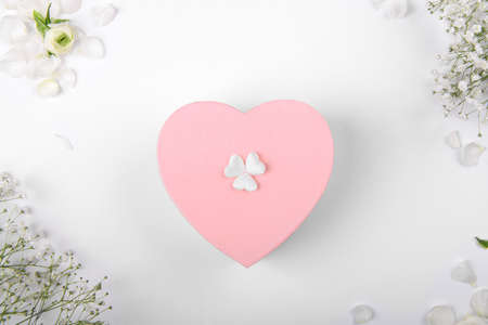 Pink heart shape gift box on a white backround with small withe flowers