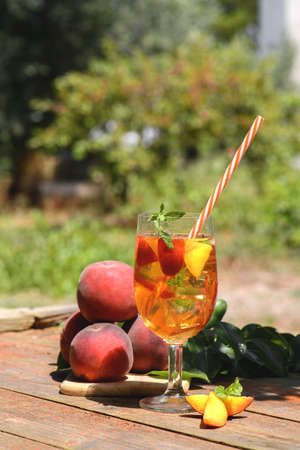 Fresh Homemade Peach Sweet Tea with Mint and Peach Slices, Summer cold fruit drink outdoors. Colorful cocktail and mocktail on a wooden backgroundの写真素材