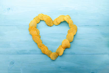 Potato chips heart shape on a blue wooden backgroundの写真素材