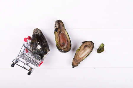 Rotten avocado in a mini food cart with two half od moldy avocado. Stop wasting food concept, eating stale food. Throwing out stale foodの写真素材