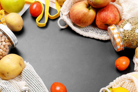 black chalkboard and various vegetables in a cotton eco sacs, string mesh bag and glass jar with...