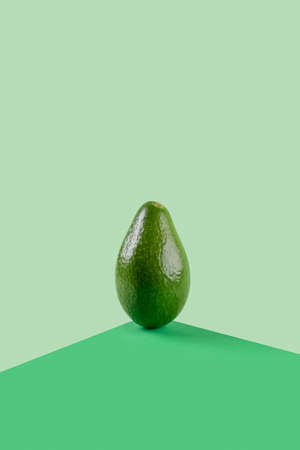 Fresh green avocado vegetables food balance on green geometric paper background, vegetarian and vegan diet balancing creative food concept, copy space. Avocado for cosmetic useの写真素材