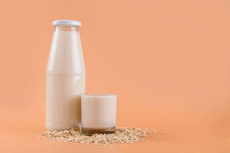 Trendy Vegan non dairy alternative milk. Oat milk in bottle and in a glass on the oat flake on...