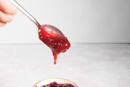 teaspoon with falling red cherry jam on a grey stone tableの写真素材