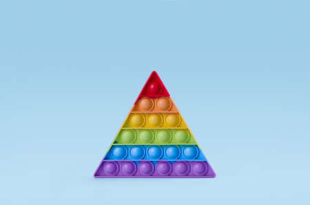 Bright rainbow toy antistress for children and adults on a blue background. Flexible sensory antistress toy pop it triangle shapeの写真素材