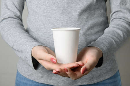 Faceless woman holding blank empty take away paper cup from bottomの写真素材