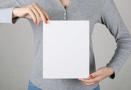 Attractive happy young woman wearing Christmas sweater holding a blank canvas in her hands.の写真素材