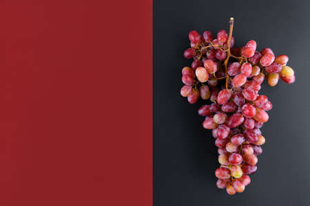 Bunch of rose grapes on a geometric double color wine red and black background, top view and copy space, modern concept of ecological winの写真素材