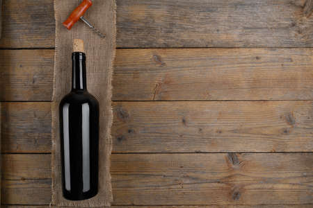 Close up of red wine bottle with stopper and corkscrew on natural wooden table background with copy spaceの写真素材