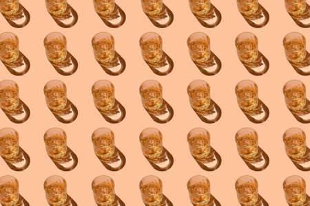 Pattern of strong alcohol drinks, hard liquors, spirits and distillates set in glasses with ice cubes: cognac, whiskey and other. Drink pattern on peach color backgroundの写真素材