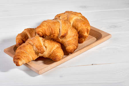Golden brown butter croissants with shadow on the white wooden background, copy spaceの写真素材