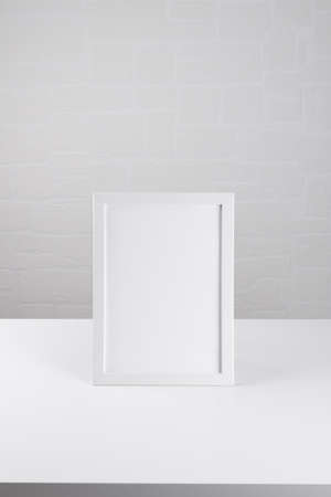 Portrait a4 white wooden frame mockup on the white table on white wall background, poster mockup....