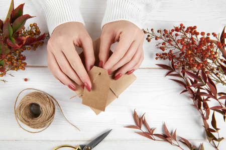 Top view of female hands wrapping autumn creative holiday present. Handmade paper gift box with...