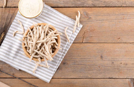 Whole grain wheat raw apulian pasta Pizzarieddi or maccaruni in a bowl on wooden table. Fresh maccheroni typical dish of Puglia, Salento Italy. Italian homemade pasta background, top view, flat layの写真素材