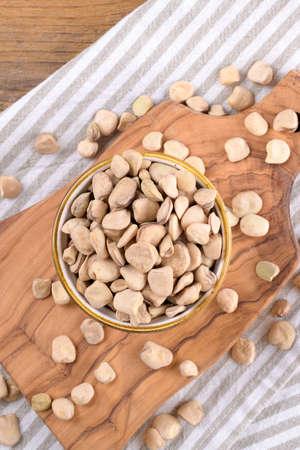 Cicerchia or indian pea on a ceramic bowl with napkin on natural wooden background, gluten free...