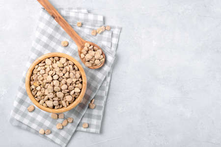 Cicerchia or Indian pea in a wooden bowl and spoon with napkin on gray table background, gluten free food. Legumes known as Lathyrus Sativus, Chickling Vetch, Blue Sweet Pea made in Puglia, top viewの写真素材
