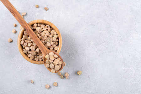 Cicerchia or indian pea in a wooden bowl and spoon on gray table background, gluten free food. Legumes known as Lathyrus Sativus, Chickling Vetch, Blue Sweet Pea made in Puglia, close up, copy spaceの写真素材
