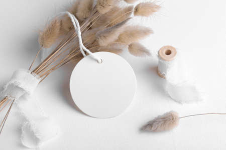 Round white tag mockup on a white background with cotton string and boho decoration, dry plants, element for packing, close up. Label product bohemian mockup copy space for text and natural eco designの写真素材