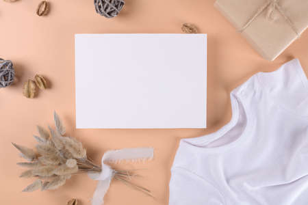 Baby shower invitation 7x5 boho card mockup with baby bodysuit and boho decotation on neutral beige backgroundの写真素材