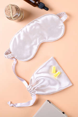 Beige sleep mask, earplugs, calming tincture and block note on neutral terracotta beige background, top view,の写真素材