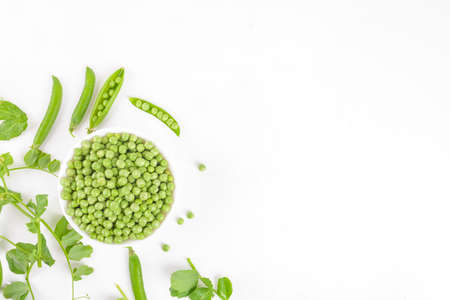 Fresh organic raw green peas in a bowl with peas pods and plants leaves on white background. Healthy eating, vegan and vegetarian legume food, raw food and detox super food, bean protein, top viewの写真素材