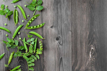Fresh organic raw green peas peas pods and plants leaves on wooden table background. legume food, raw bean proteinの写真素材
