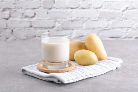 Vegan potato milk and potato on grey stone table background. Plant based alternative milk replacer and lactose freeの写真素材