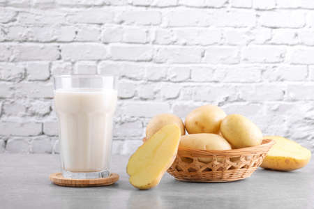 Vegan potato milk and potato on grey stone table background. Plant based alternative milk replacer and lactose freeの写真素材