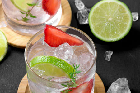 Fresh strawberry mojito cocktail. Two glasses with cold summer strawberry soda drink with strawberry, ice and lime, decorated wiht thyme on dark background. Iced strawberry lemonade, close upの写真素材