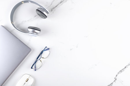 Modern office workspace with laptop, mouse, eyeglasses and headphone. Business concept flat lay on white marble background. digital communication. Creativity and innovation concept, copy spaceの写真素材