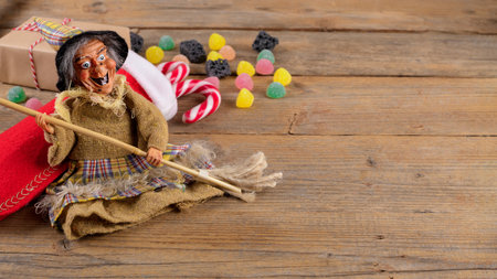 The witch Befana and red stocking with sweet coal and candy on rustic wooden background. Italian Epiphany day traditionの写真素材