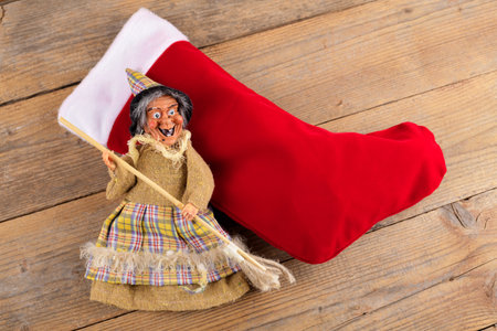 The funny witch Befana and red stocking with sweet coal and candy on wooden background. Italian Epiphany day traditionの写真素材